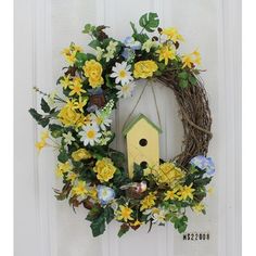 a birdhouse wreath with yellow and white flowers