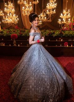 a woman in a silver dress standing next to a chandelier