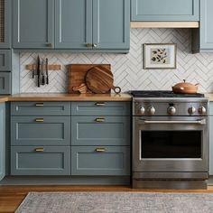 a kitchen with blue cabinets and stainless steel stove top oven, wood cutting board on the counter