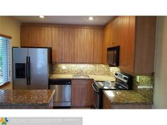 an empty kitchen with granite counter tops and stainless steel refrigerator, stove, dishwasher and microwave