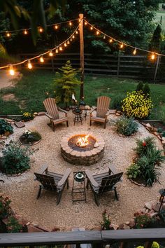 an outdoor fire pit surrounded by chairs and lights