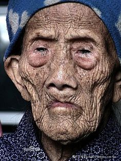 an old woman with wrinkles on her face and head, looking at the camera