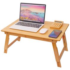 a laptop computer sitting on top of a wooden table next to a phone and mouse