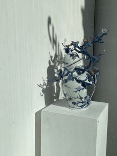 a white vase sitting on top of a cement block next to a shadow of a plant