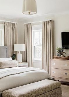 a bedroom with white walls and beige curtains