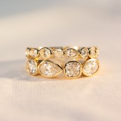 a gold ring with five pear shaped diamonds on it's side, sitting on a white surface