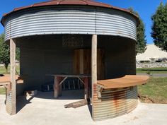 an old round building with two benches and a table in the middle outside on concrete