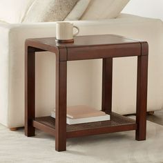 a coffee table with a book on it in front of a white couch and pillows