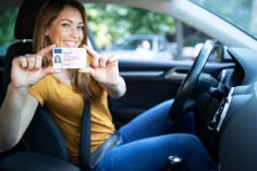 a woman sitting in the back seat of a car holding up a small business card