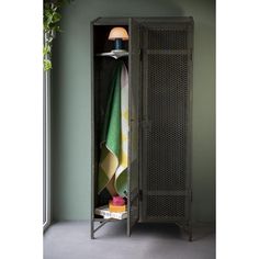 an open metal cabinet with towels hanging on the door and a potted plant next to it