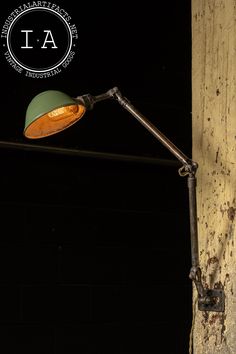 an old lamp on the side of a building at night with dark lighting in the background