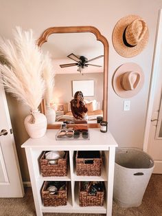 a woman taking a selfie in front of a mirror with baskets on the floor