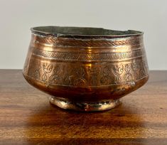 an old metal bowl sitting on top of a wooden table