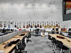 an office with guitars hanging on the wall and desks in front of them,