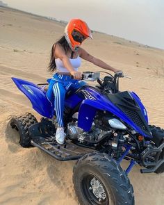 a woman riding on the back of a blue four - wheeler in the sand dunes