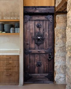 an old wooden door in the middle of a stone wall with shelves on either side