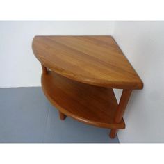 a small wooden table sitting on top of a gray floor next to a white wall