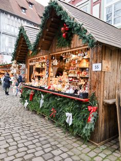 an outdoor market with christmas decorations and teddy bears on the outside, along with people walking by