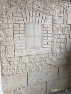 a white brick wall with a window on the side and bricks below it that have been carved into them