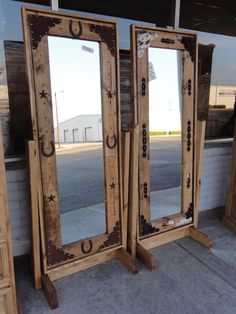 two wooden mirrors sitting next to each other on top of a cement floor in front of a building