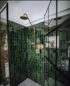 a green tiled shower in a bathroom with black and white tiles