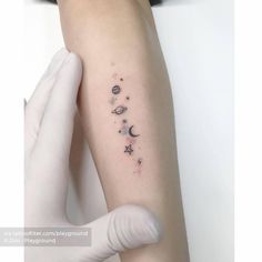 a woman's arm with tattoos on it that include planets, stars and the moon