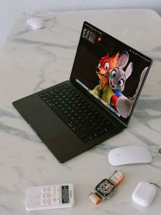 an open laptop computer sitting on top of a white table next to a mouse and cell phone