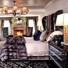 a bedroom with a fireplace in the middle and lots of pillows on the bed next to it