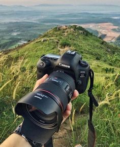 a person taking a photo with a camera on top of a hill