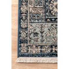 the blue and beige area rug with fringes on it is laying on a wooden floor