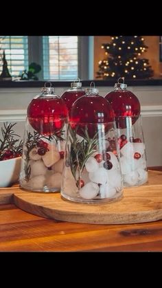 three glass vases filled with red and white balls on top of a wooden table