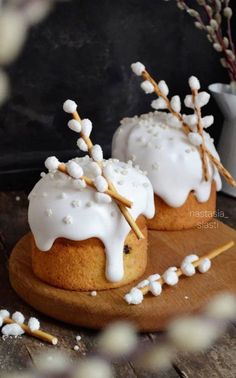 two cakes with white frosting and sprinkles sitting on a wooden board