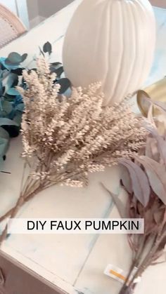 some dried flowers are on a table with a white ball in the background that says diy faux pumpkin