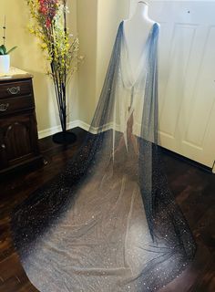 a wedding dress on display in front of a vase with flowers and an open veil