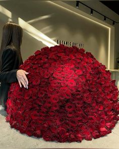 a woman standing next to a giant red rose covered umbrella