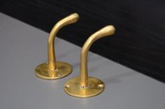 two gold colored metal hooks on a gray surface