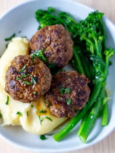 meatballs, mashed potatoes and broccoli in a white bowl on a wooden table