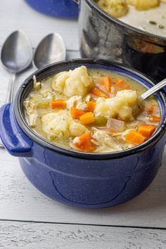 there is a bowl of soup with carrots and cauliflower on the table