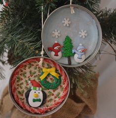 two ornaments hanging from a christmas tree with snowman and penguin decorations on it's ornament