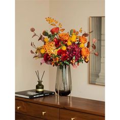 a vase filled with colorful flowers on top of a wooden dresser