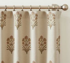 the curtain is hanging in front of a white wall with gold and brown designs on it