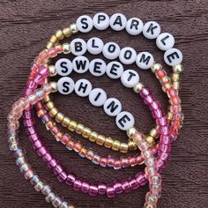 several bracelets that say sparkle, bloom, sweet and shine on top of each other