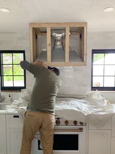 a man standing on top of a kitchen counter in front of a stove and oven