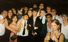 a group of people standing next to each other posing for a photo with their thumbs up