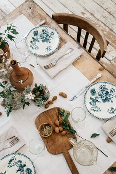 a wooden table topped with plates and glasses