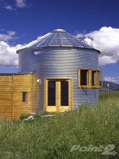 a round building sitting on top of a lush green field next to a blue sky