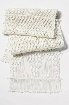 three pieces of white crocheted fabric with fringes on top of each other