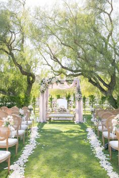 an outdoor ceremony setup with white flowers and greenery on the grass, surrounded by trees