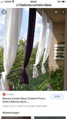 purple and white drapes are hanging from the side of a balcony over green grass