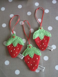 two felt strawberry ornament hanging on a polka dot table